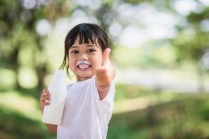 Cute asian little child girl is drinking a milk, soft focus photo