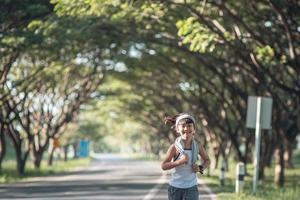 happy child girl running in the park in summer in nature. warm sunlight flare. asian little is running in a park. outdoor sports and fitness, exercise and competition learning for kid development. photo