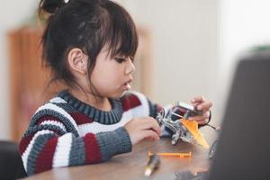 Inventive kid constructing robot cars at home photo