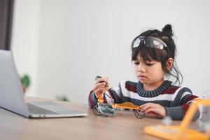 Inventive kid constructing robot cars at home photo