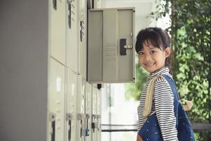 Preparing to lesson. Little school girl putting his bag in a locker in changing room before the lesson. photo