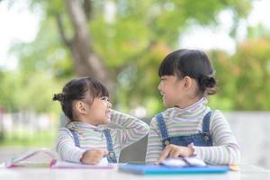 dos estudiantes niñas asiáticas leyendo el libro en la mesa foto