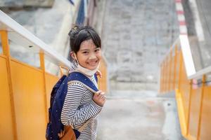 De vuelta a la escuela. linda niña asiática con mochila y yendo a la escuela foto