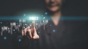 welcome year 2022 New year 2021 change to 2022 concept, woman hand touching on 2022 virtual screen. photo