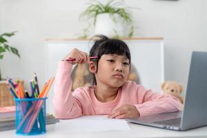 Unhappy little Caucasian girl child sit at table at home feel lazy unmotivated doing homework assignment. Upset distressed small 7s kid prepare school task, learn study with books. Education concept. photo