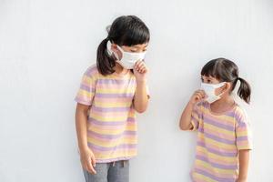 Sibling Little girl wearing a mask to stop coronavirus outbreak.Quarantine Asian sibling.Covid-19 coronavirus and pandemic virus symptoms. photo