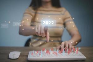 bienvenido año 2022 año nuevo 2021 cambio al concepto 2022, mano de mujer de negocios tocando en la pantalla virtual 2022. foto