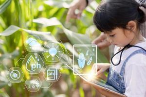 The little girl uses a tablet to analyze the growth of plants in the agricultural plot and visual icon., the agricultural technology concept. smart farming learning Concept photo