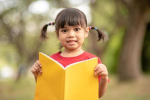 niña bonita la niña está feliz con el libro foto