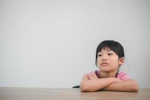 niña asiática descansa sus mejillas en los puños con cara malhumorada foto