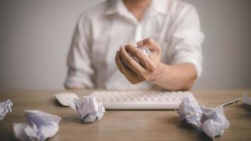 A frustrated discouraged man crumpling a paper at work on the desk. photo