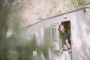 feliz hermosa mujer bastante asiática por la ventana de la autocaravana foto