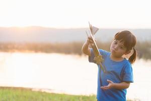 sueña con un niño que vuela jugando con un avión de juguete contra el cielo al atardecer foto