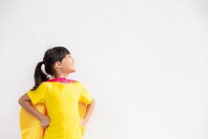 Funny little girl playing power superhero over white background. superhero concept. photo