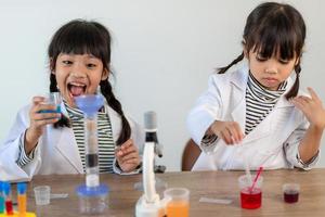 education, science, chemistry and children concept - kids or students with test tube making experiment at school laboratory photo