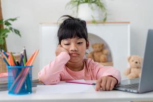 Unhappy little Caucasian girl child sit at table at home feel lazy unmotivated doing homework assignment. Upset distressed small 7s kid prepare school task, learn study with books. Education concept. photo