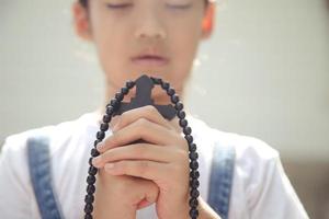 Little Asian girl praying with holding the cross, Christian concept. photo