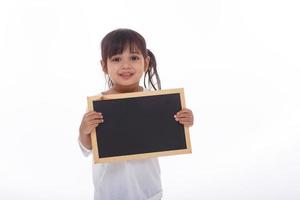 un niño asiático muestra la pizarra negra en un fondo aislado foto