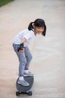 Cute little girl playing skateboard or surf skate in the skate park photo