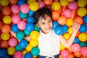 Happy asian girl playing in colorful balls pool photo