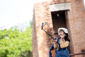 Happy Asian traveler girl takes a photo with a smartphone camera.