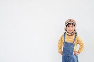 sueños de vuelo niña pequeña jugando con un sombrero de piloto sobre fondo blanco foto