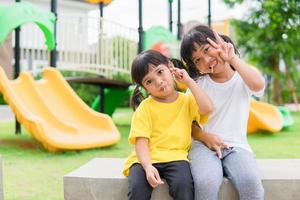 dos niños juegan y comen piruletas en el patio de recreo foto