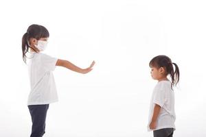 Social distance concept. Two Asian kids wearing mask standing distance of 2 meter from other people keep distance protect from COVID-19 and The risk of infection to others. photo