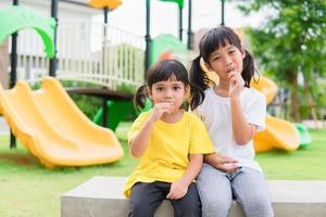 dos niños juegan y comen piruletas en el patio de recreo foto