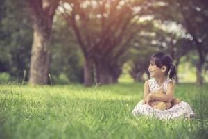 little girl hugging her teddy bear in park.Vintage Color photo