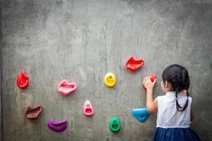 little girl climbing a rock wall photo