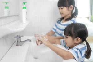 Little Asian girls wash their hands in the bathroom. Soft focus. Copy space. photo