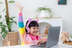 Smiling little Asian girl have a video call distant class with teacher using laptop, social distance during quarantine isolation during the Coronavirus photo