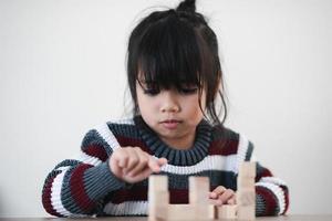 Cheerful Asian girl playing with wooden building blocks. Having fun and learning creativity. smart kid concept. photo