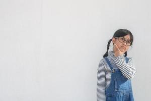 Cute Asian small girl wearing glasses and thinking photo