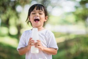 Cute asian little child girl is drinking a milk, soft focus photo