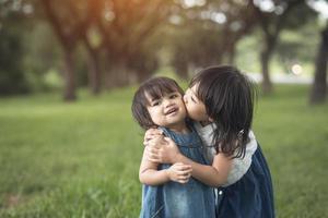 happy family. little girls sisters kissing and laughing in the summer outdoors photo
