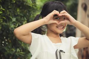 manos de niña haciendo una forma de corazón sobre fondo blanco foto