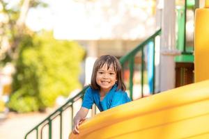 linda niña divirtiéndose en un patio de recreo al aire libre en verano foto