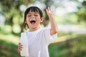 Cute asian little child girl is drinking a milk, soft focus photo
