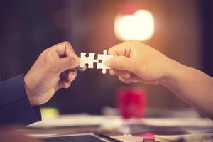 two hands of businessman to connect couple puzzle piece with sky background.Jigsaw alone wooden puzzle against sun rays.one part of whole.symbol of association and connection.business strategy photo