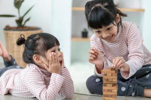 Asian sibling  girl playing wooden stacks at home photo