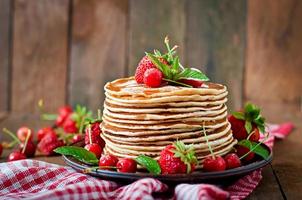 Pancakes with berries and syrup in a rustic style photo