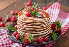 Pancakes with berries and syrup in a rustic style photo