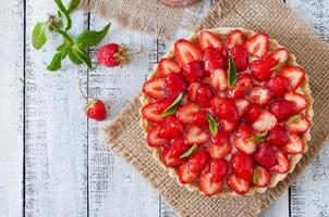 Tart with strawberries and whipped cream decorated with mint leaves photo