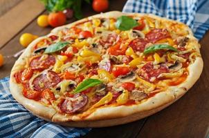pizza con salami, tomate, queso y champiñones foto