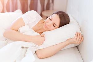 Serene calm woman sleeping in comfortable bed lying on soft pillow orthopedic photo