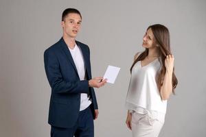 Business partner gives certificate to happy woman on gray background. Caucasian photo