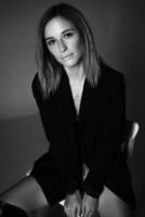 woman posing sitting on a chair in jacket and lingerie, black and white photo