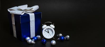 beautiful blue gift box and white alarm clock on black background photo